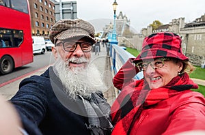 Happy senior couple taking selfie in london - Old trendy people having fun with technology trends - Travel and joyful elderly
