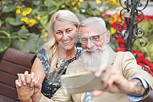 Happy senior couple taking selfie with mobile smart phone outdoor - Mature retired people having fun with new technology