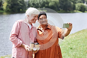 Happy senior couple taking selfie photo outdoors together enjoying walk in park