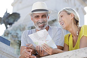 happy senior couple tourists with map