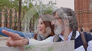 Happy senior couple of tourists sightseeing Barcelona city with map