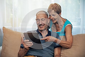 Happy senior couple using digital tablet at home