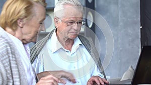 Happy senior couple using social media with laptop computer