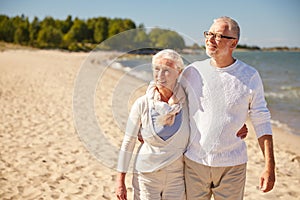 Happy senior couple walking along summer beach