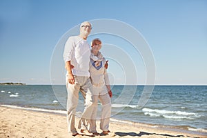 Happy senior couple walking along summer beach