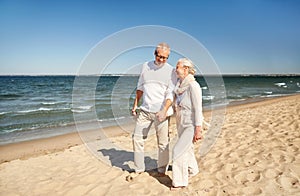 Happy senior couple walking along summer beach