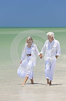 Happy Senior Couple Walking Holding Hands on Beach