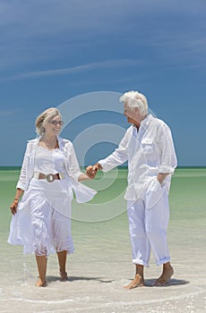Happy Senior Couple Walking Holding Hands On Beach