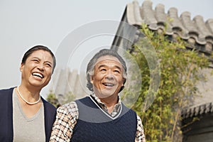 Happy senior couple walking outdoors by traditional building in Beijing