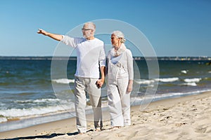 Happy senior couple walking on summer beach