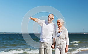 Happy senior couple walking on summer beach