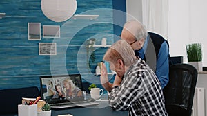 Happy senior couple waving during video conference with nephews