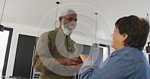 Happy senior diverse couple dancing in kitchen at retirement home