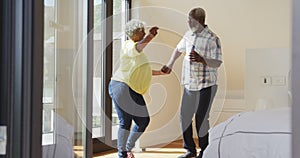 Happy senior diverse couple dancing in living room at retirement home