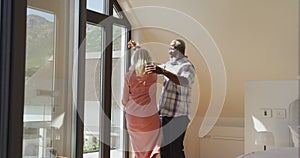 Happy senior diverse couple dancing in living room at retirement home