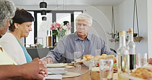 Happy senior diverse people praying before dinner at retirement home