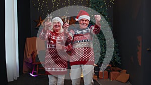 Happy senior family couple celebrating Christmas at home, clinking glasses and drinking champagne