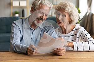 Happy senior family couple reading paper document.