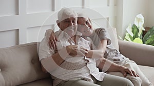 Happy senior family couple sit on sofa at home, portrait