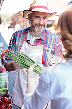 Happy senior farmer selling organic vegetables in a farmer`s marketplace