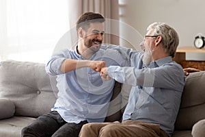 Happy senior father embracing young son giving fist bump