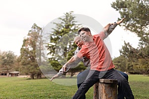 Happy senior father with his young son with Down syndrome sitting and having fun in park.