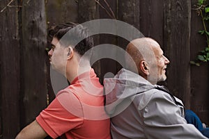 Happy senior father with his young son with Down syndrome sitting and having fun in park.