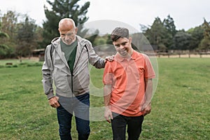 Happy senior father with his young son with Down syndrome walking in park together.