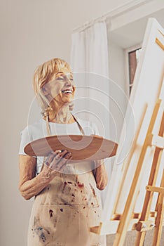 Happy senior female person looking at her easel