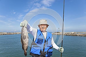 Happy senior fisherman showing large grouper