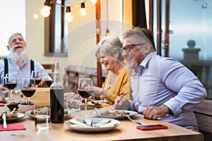 Happy senior friends having fun dining together on house patio