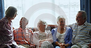 Happy senior friends interacting with each other while relaxing on sofa 4k
