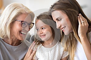 Happy senior grandma embracing kid granddaughter and daughter ha