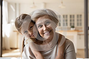 Happy senior grandma look at camera piggybacking girl beloved grandkid