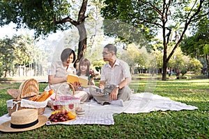 Happy senior grandparent together playing with little grandchild girl and party in park. Family leisure concept