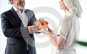 Happy senior husband handing over present to his wife