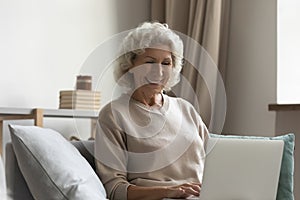 Happy senior lady making video call on laptop from home