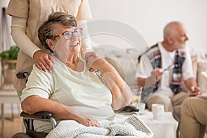 Happy senior lady sitting at wheelchair in nursing home for elderly