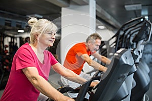 Happy senior lady training on spin bike at gym