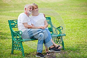 Happy senior loving couple relaxing at park embracing together in morning time. old people sitting on a bench in the autumn park