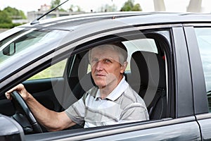 Happy senior male sitting in car on driver seat