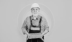 happy senior man bricklayer in hard hat on yellow background