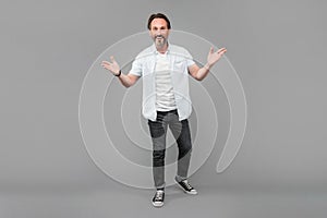 Happy senior man in casual gesticulate with open arms grey background, welcome