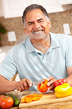 Happy senior man chopping vegetables