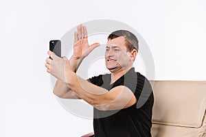 Happy senior man communicates non-verbally via video dialogue while sitting home in a chair on a white background photo