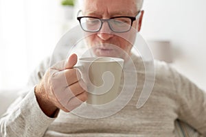 Happy senior man drinking tea or coffee at home