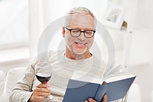 Happy senior man drinking wine and reading book
