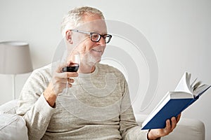 Happy senior man drinking wine and reading book