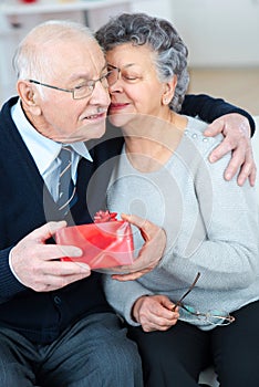 Happy senior man giving gift to wife