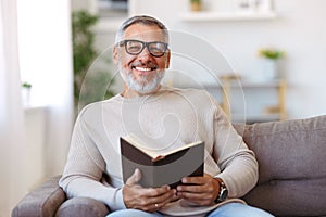 Contento uomo grigio capelli occhiali lettura un libro sul sta riposando soggiorno 